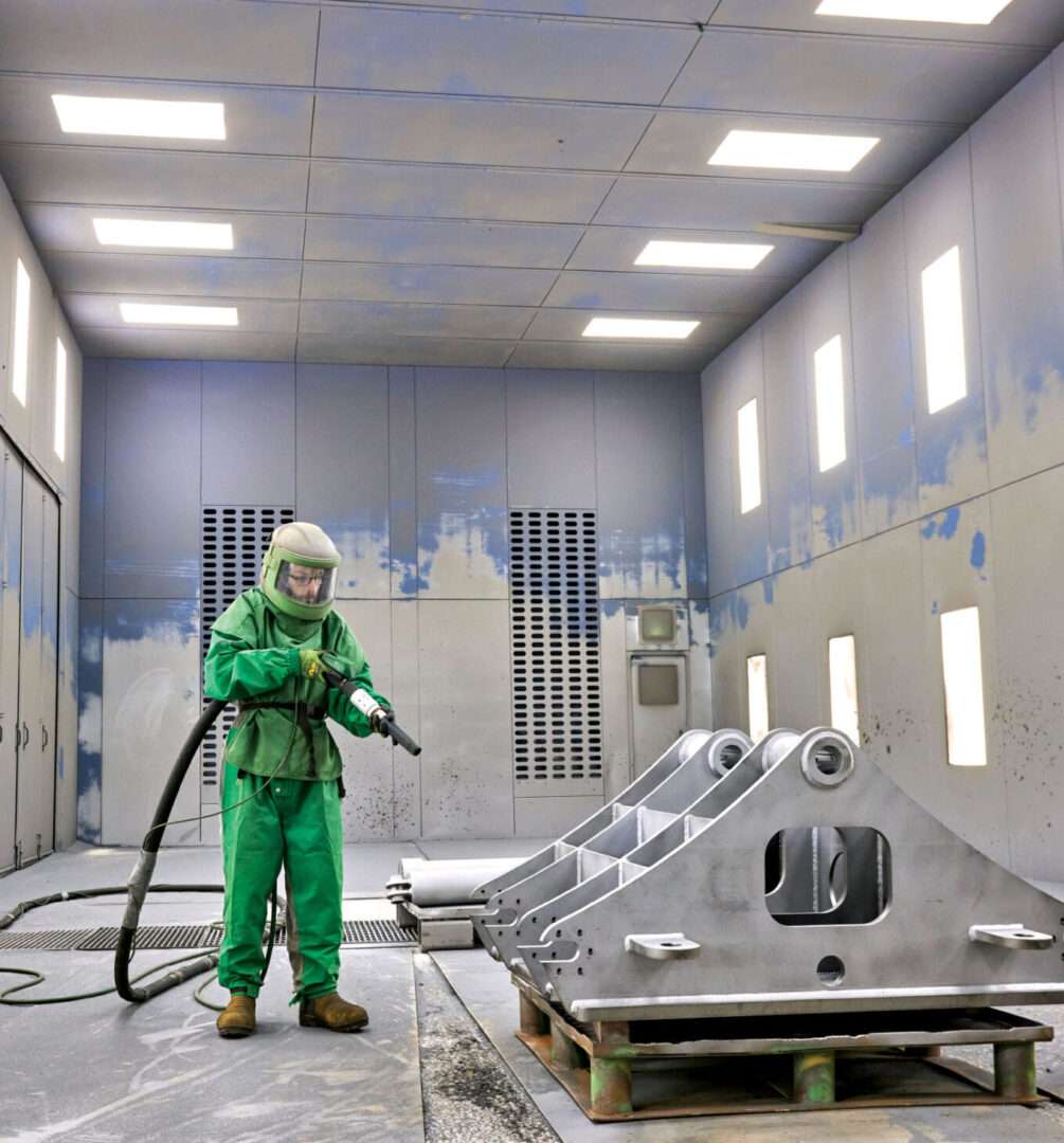 Employee in PPE equipment ready to spray part