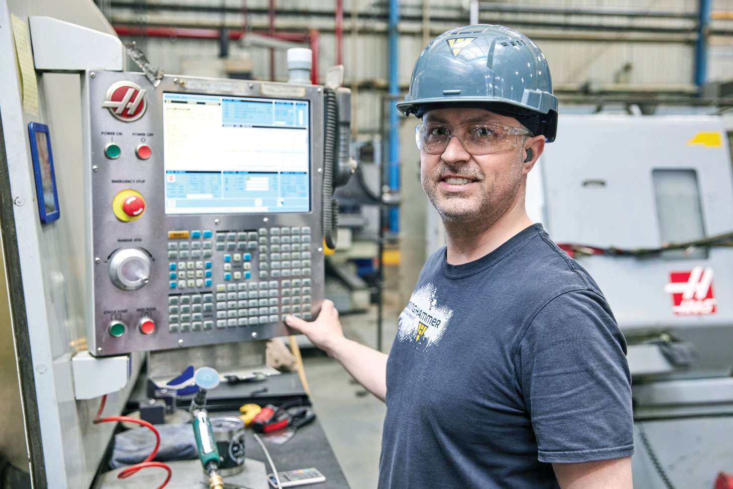 Employee with smile posing for photo in front of electronic display