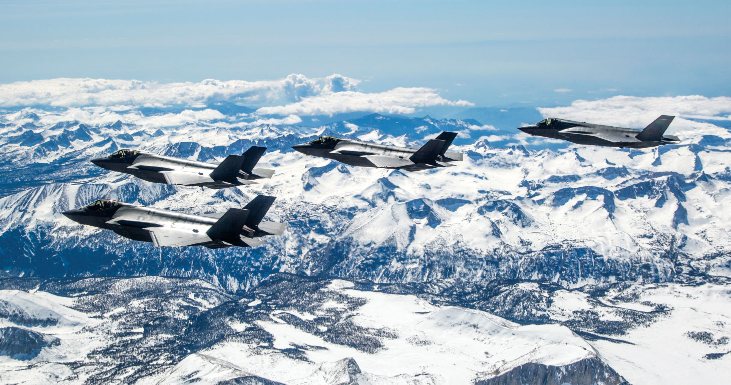 Four CF-35A fighter jets flying above snowy mountaintops