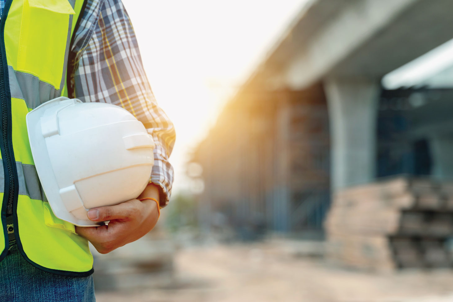 Mid-torso view of worker holding hardhat against hip