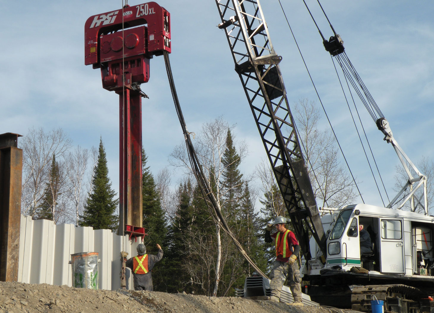 Workers operating heavy machinery driving sheet wall piles