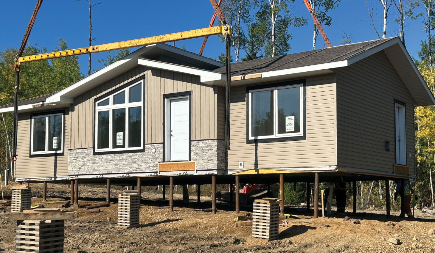 Crane installing home on piles