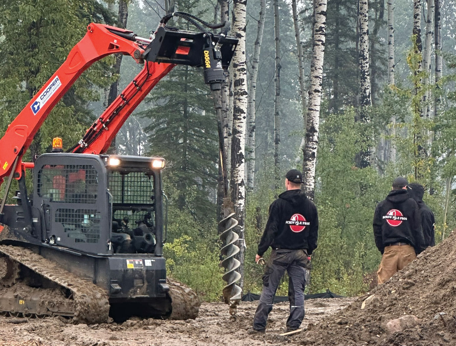 Worker watching auger about to drill in ground