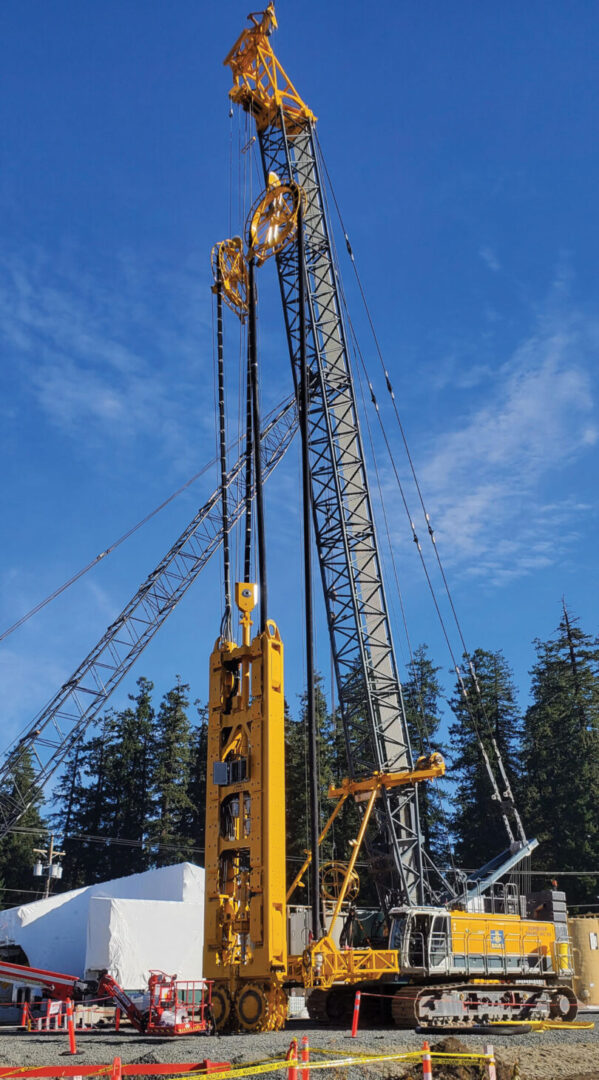 Pile driving equipment with trees and blue sky in background