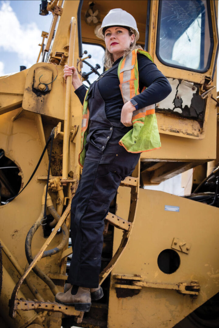 Woman in Dirty Seahorse Zenith coveralls on yellow tractor