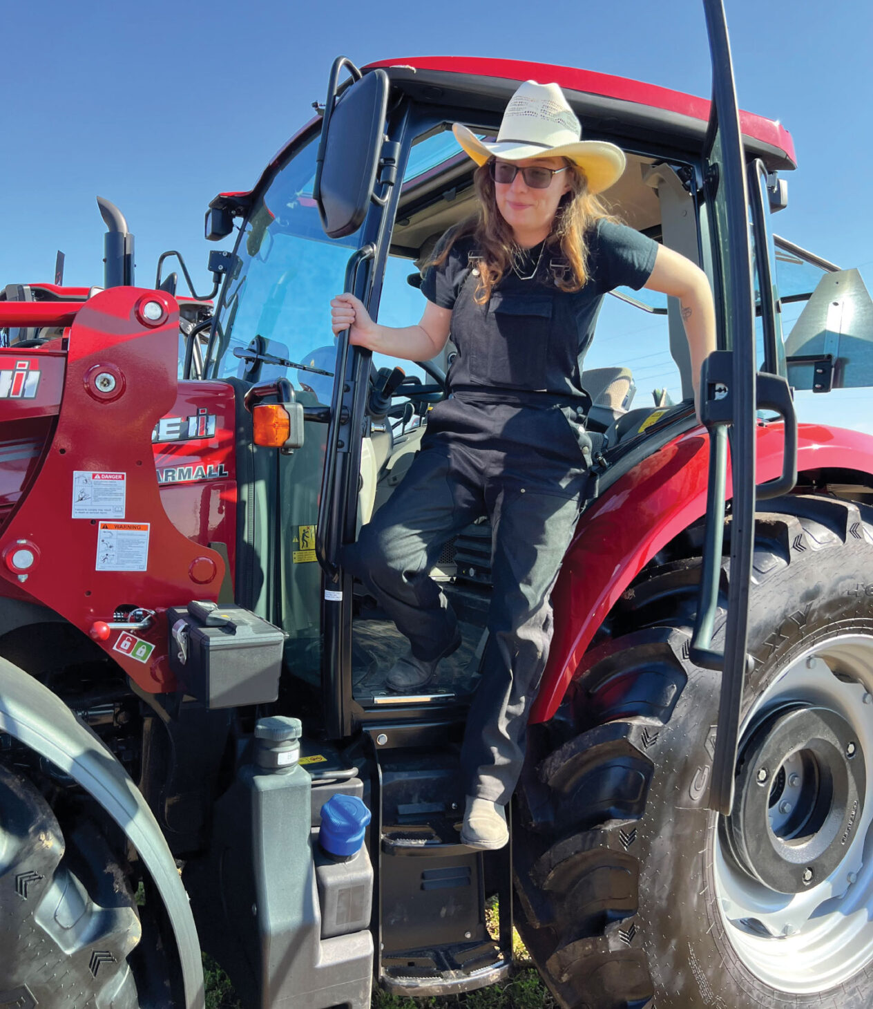 Woman in Dirty Seahorse Zenith coveralls on red tractor